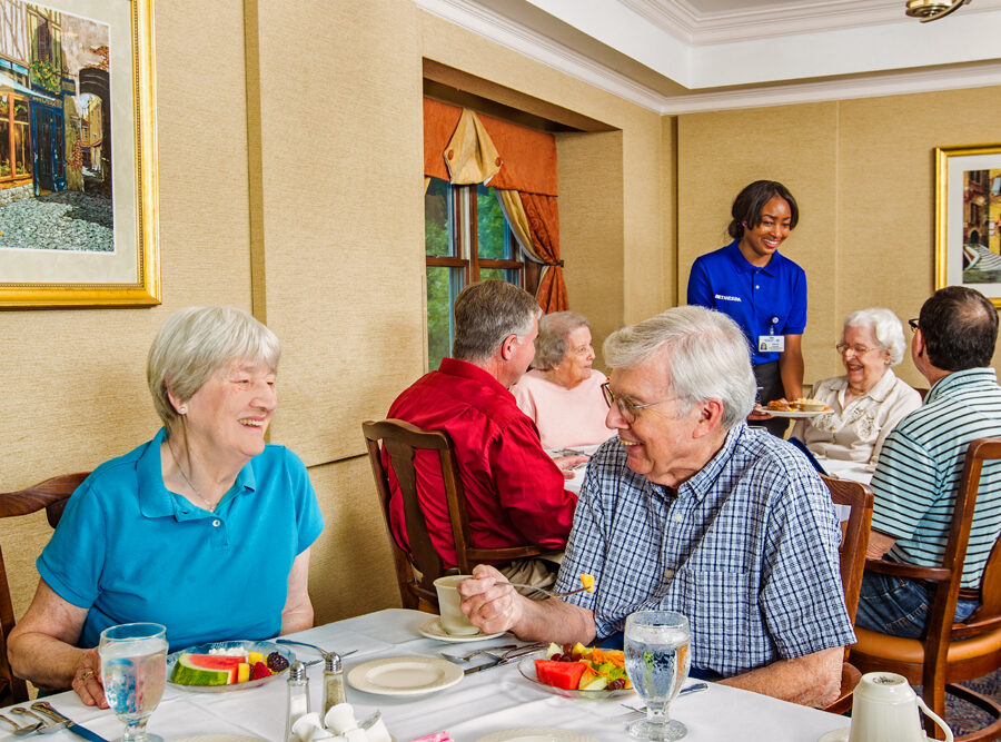 several seniors dine in a nice looking restaurant with a server attending them