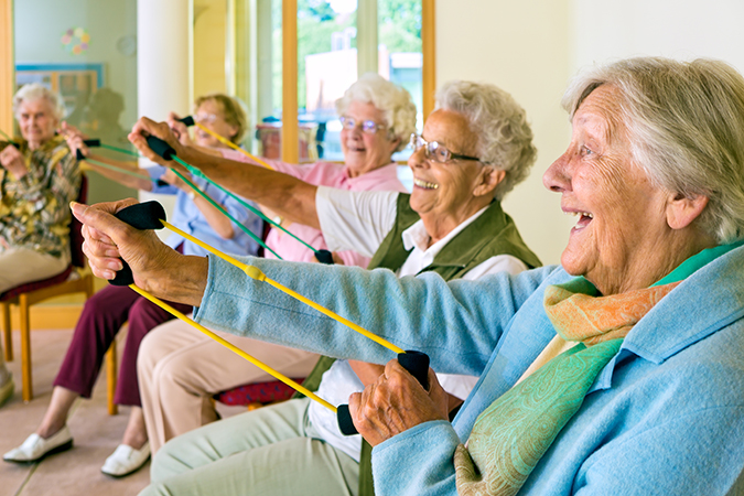 A group of seniors do seated exercises while holding resistance bands in their hands