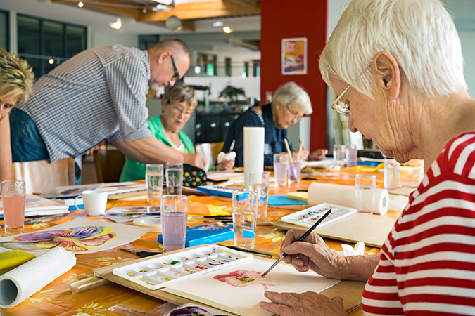 senior women and men paint at Bethesda Charless Village, with an instructor helping