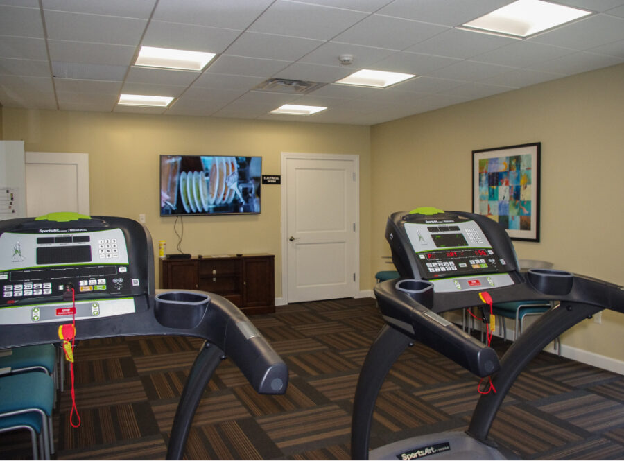 A photo of The Oaks fitness center with treadmills and TV