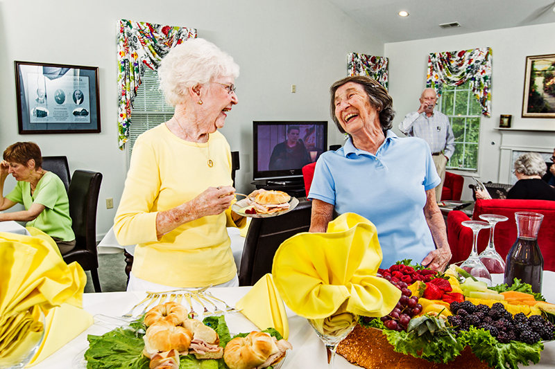 Two senior women laugh over breakfast