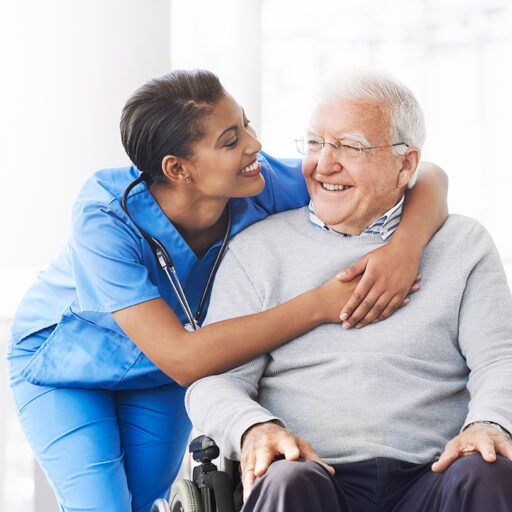 young female nurse hugging the shoulders of a senior man in a wheelchair