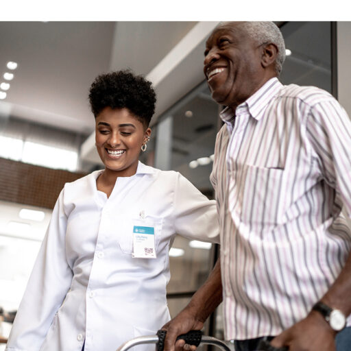 Senior man using a walker with the assistance of a young female skilled nursing professional at Barnes-Jewish Extended Care