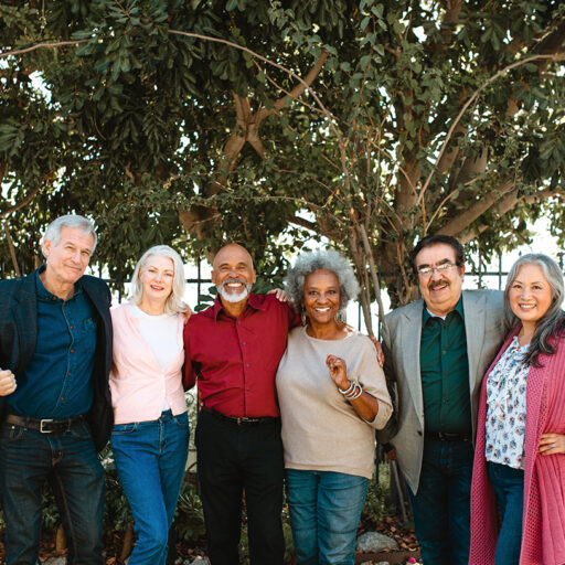 A group of six seniors—three men and three women—pose for a photo in front of a tree.