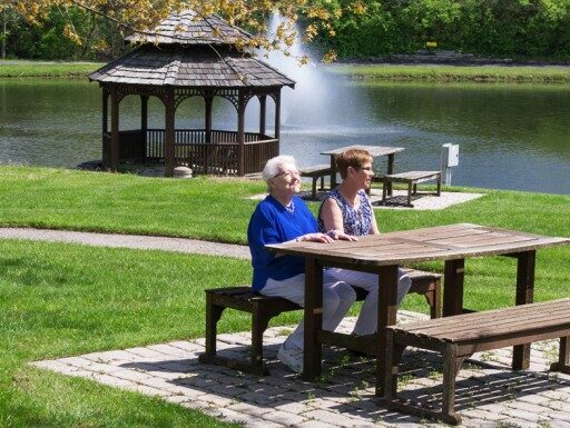 Seniors enjoying a sunny day in the garden near a lake at an independent living community