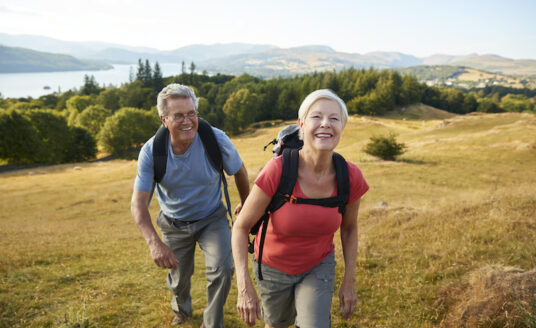 Senior aged man and woman hiking along a valley, reaping the benefits of exploring nature