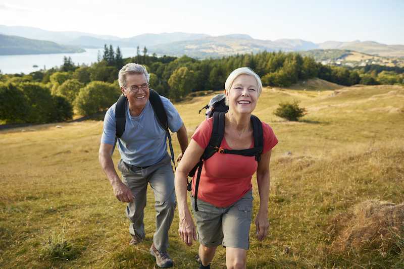 Senior aged man and woman hiking along a valley, reaping the benefits of exploring nature