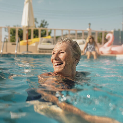 Senior aged woman practicing summer heat safety by swimming in a pool