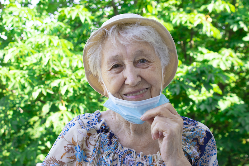 Older woman removing her face mask due to new covid guidelines for seniors
