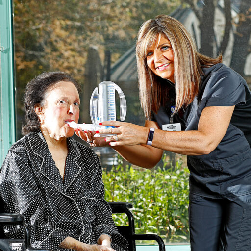 A female nurse provides respiratory therapy to a senior woman