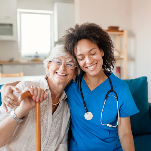 a young female nurse and a senior woman with a cane hug each other's shoulders and smile at Bethesda Southgate