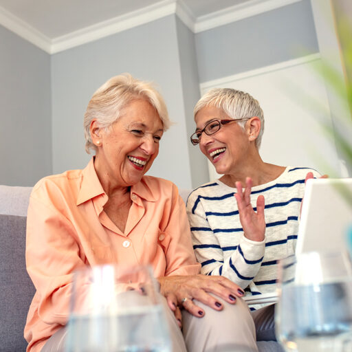 Two happy senior women talking and laughing while sitting on a couch