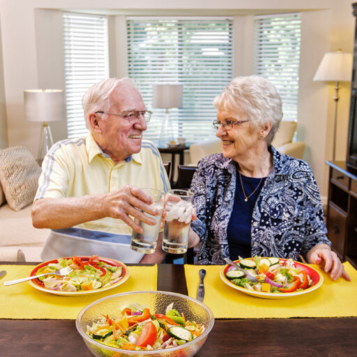 A senior man and woman enjoy a colorful salad in their home at Bethesda Terrace