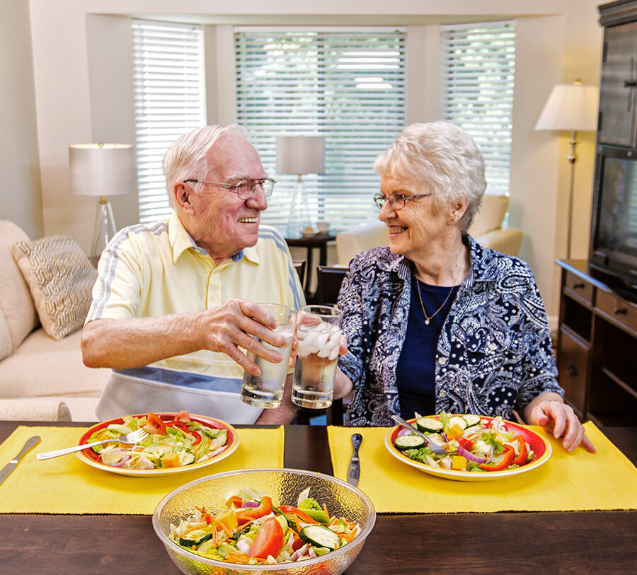 A senior man and woman enjoy a colorful salad in their home at Bethesda Terrace