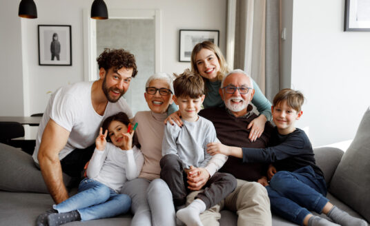 Seniors stay connected with friends and family in a big group photo with three kids, the adult parents and a senior man