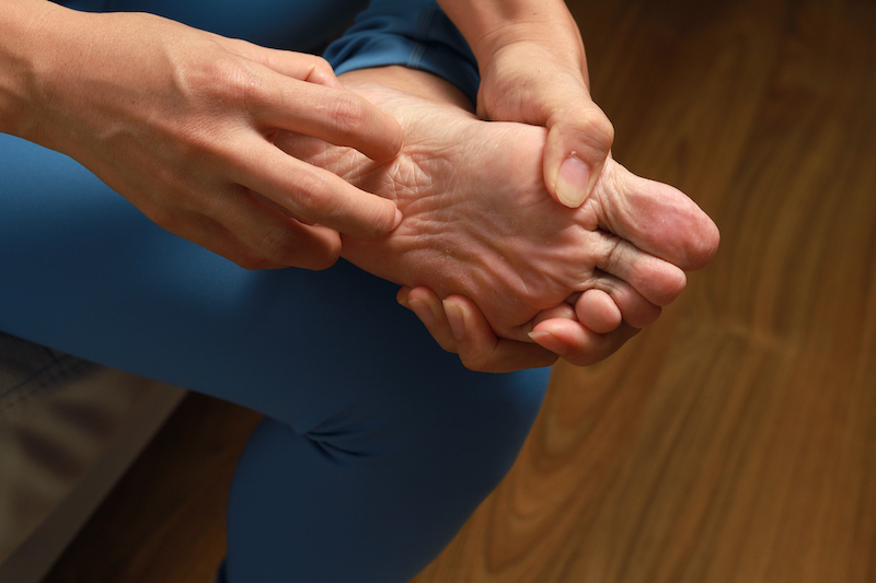 Person holds their foot which is in pain due to poor foot health