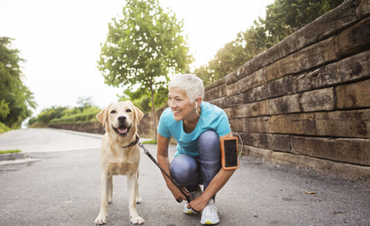 Senior woman walking her dog during fall to follow autumn exercise tips