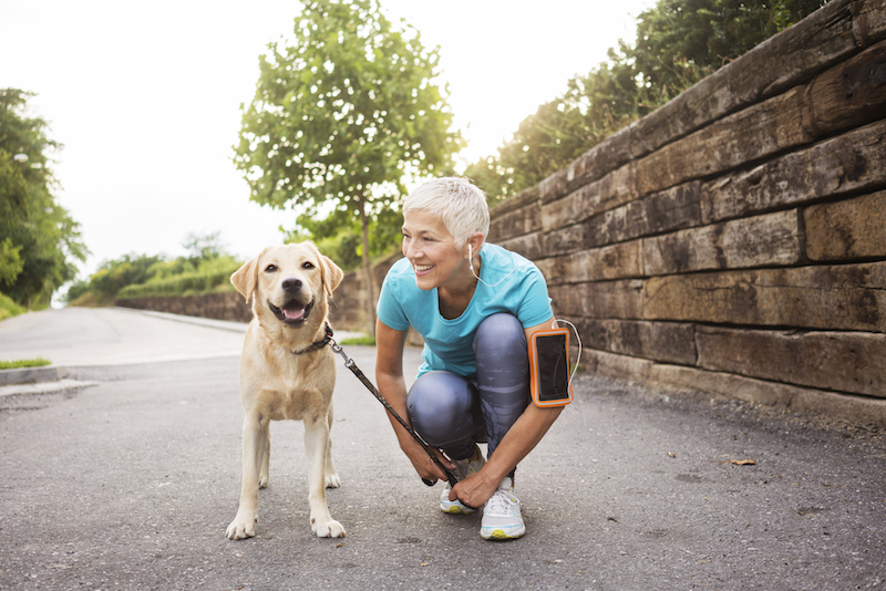 Senior woman walking her dog during fall to follow autumn exercise tips