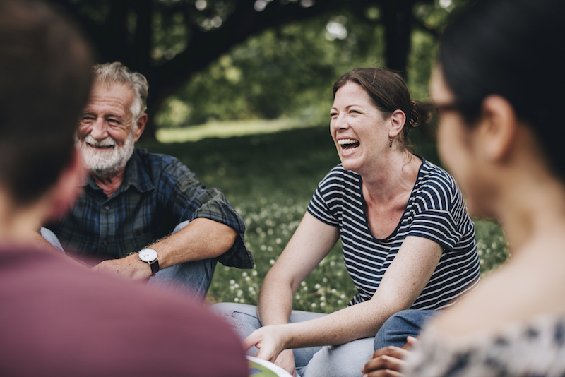 Older adults reap the benefits of nostalgia by reminiscing together, seated in a circle outdoors during springtime.
