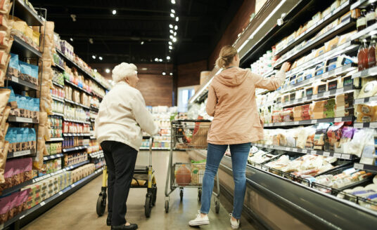 A young woman helps a senior woman with shopping at the grocery store