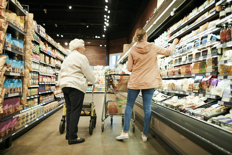 A young woman helps a senior woman with shopping at the grocery store