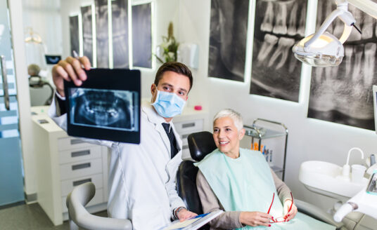 Senior man receives preventive dental care at his dentists office as he sits in the chair and looks at an xray