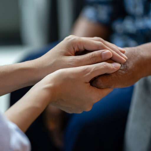 A person holding hands with their senior loved one in hospice care.