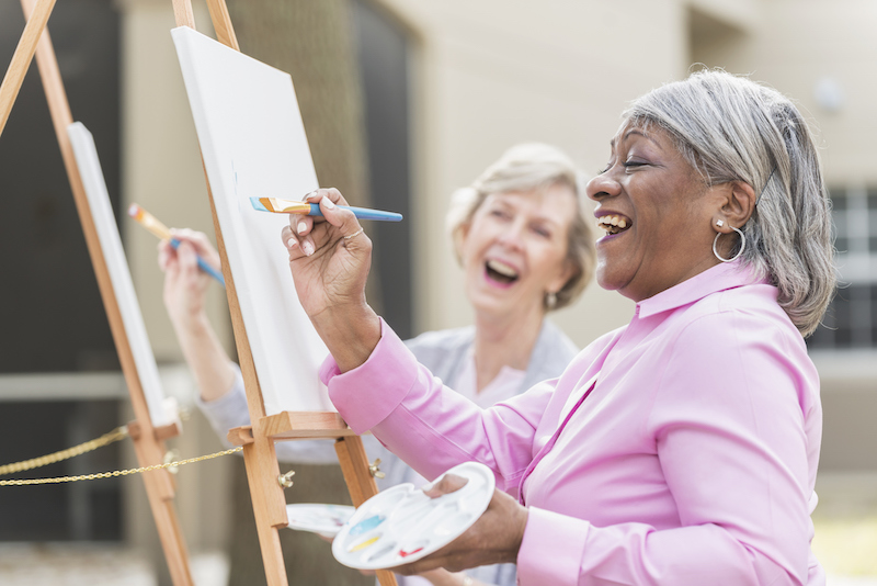 two senior women painting during art therapy