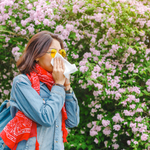 women blowing her nose due to seasonal allergies