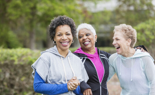 Three older women enjoying the benefits of laughter outside
