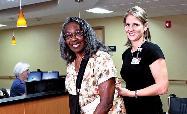 A senior african american female wearing a sling is being helped by a young blonde nurse