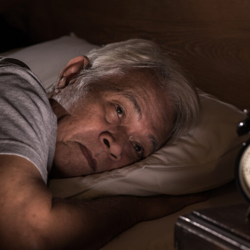 Senior man lying in bed cannot sleep from sleeping patterns changing