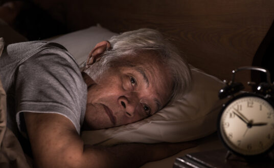 Senior man lying in bed cannot sleep from sleeping patterns changing