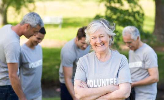 Smiling older woman wearing a volunteer shirt and experiencing the benefits of volunteering