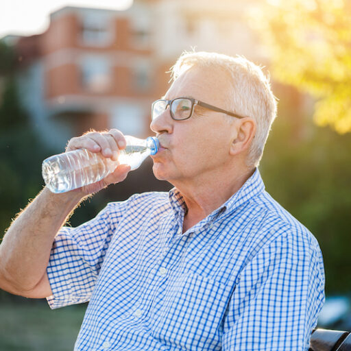 senior man drinking water and avoiding the dangers of humidity