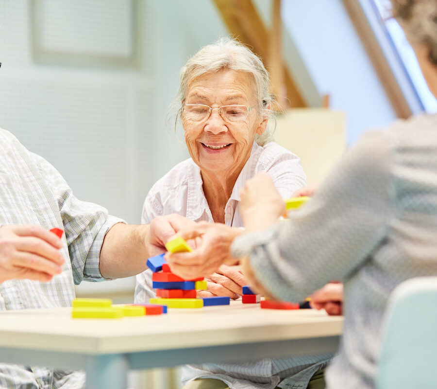 A group of seniors stacking small blocks to practice manual dexterity in an independent living community.
