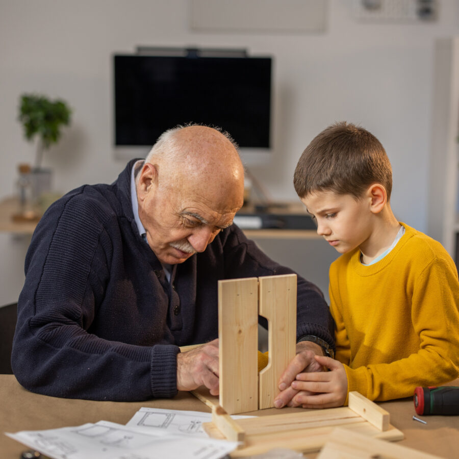 Older adult with young child showing manual dexterity with a woodworking project