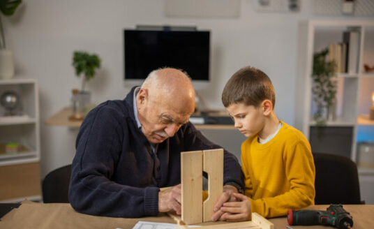 Older adult with young child showing manual dexterity with a woodworking project
