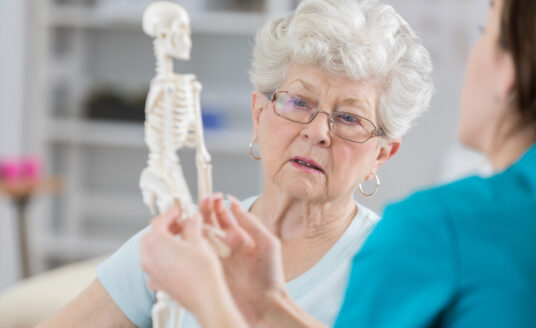 Senior woman discusses aging bones with physical therapist