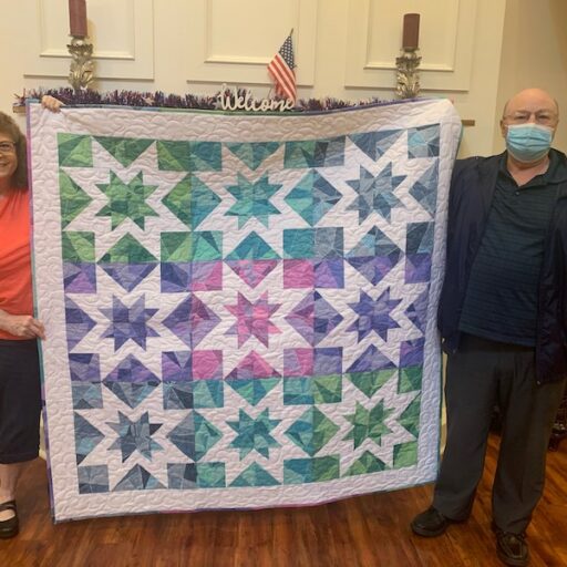 Man and woman holding a quilt which was donated to raised money for senior living expenses