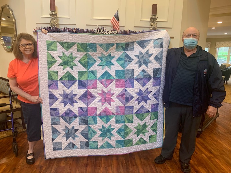 Man and woman holding a quilt which was donated to raised money for senior living expenses