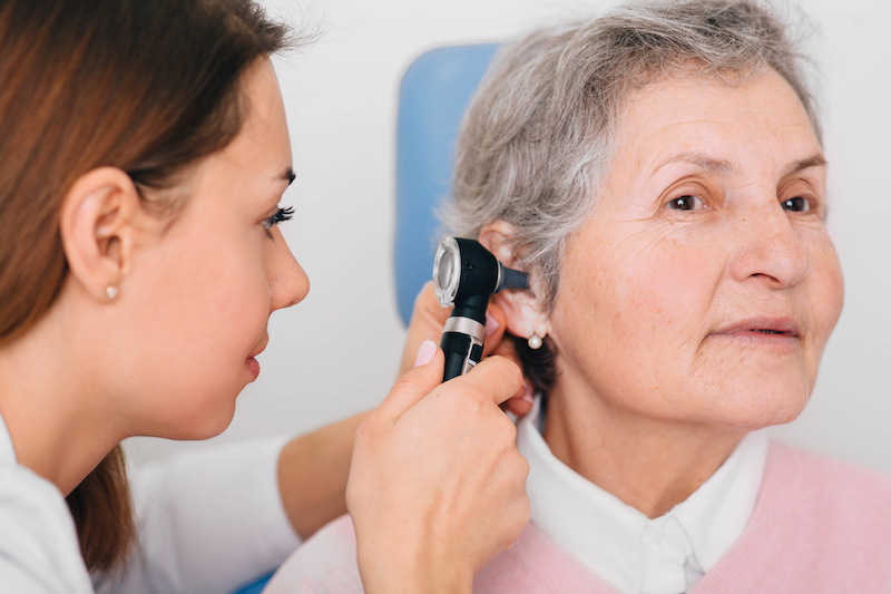 doctor checking elderly woman for hearing loss