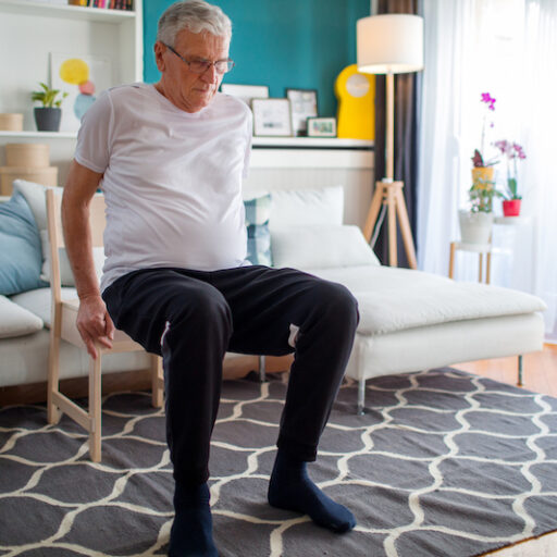 Senior man doing chair exercises at home