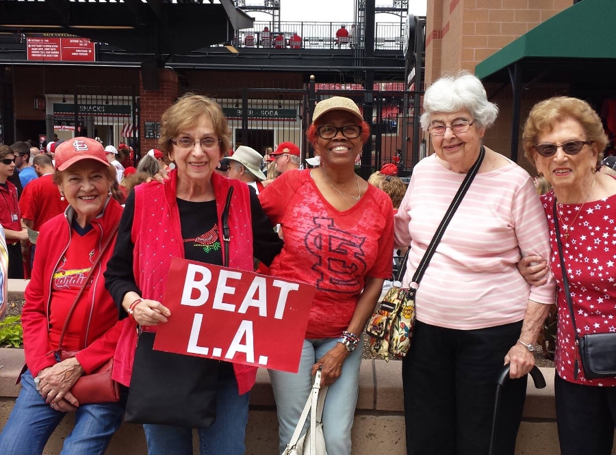 4 women dressed in red at a Cardinals baseball game