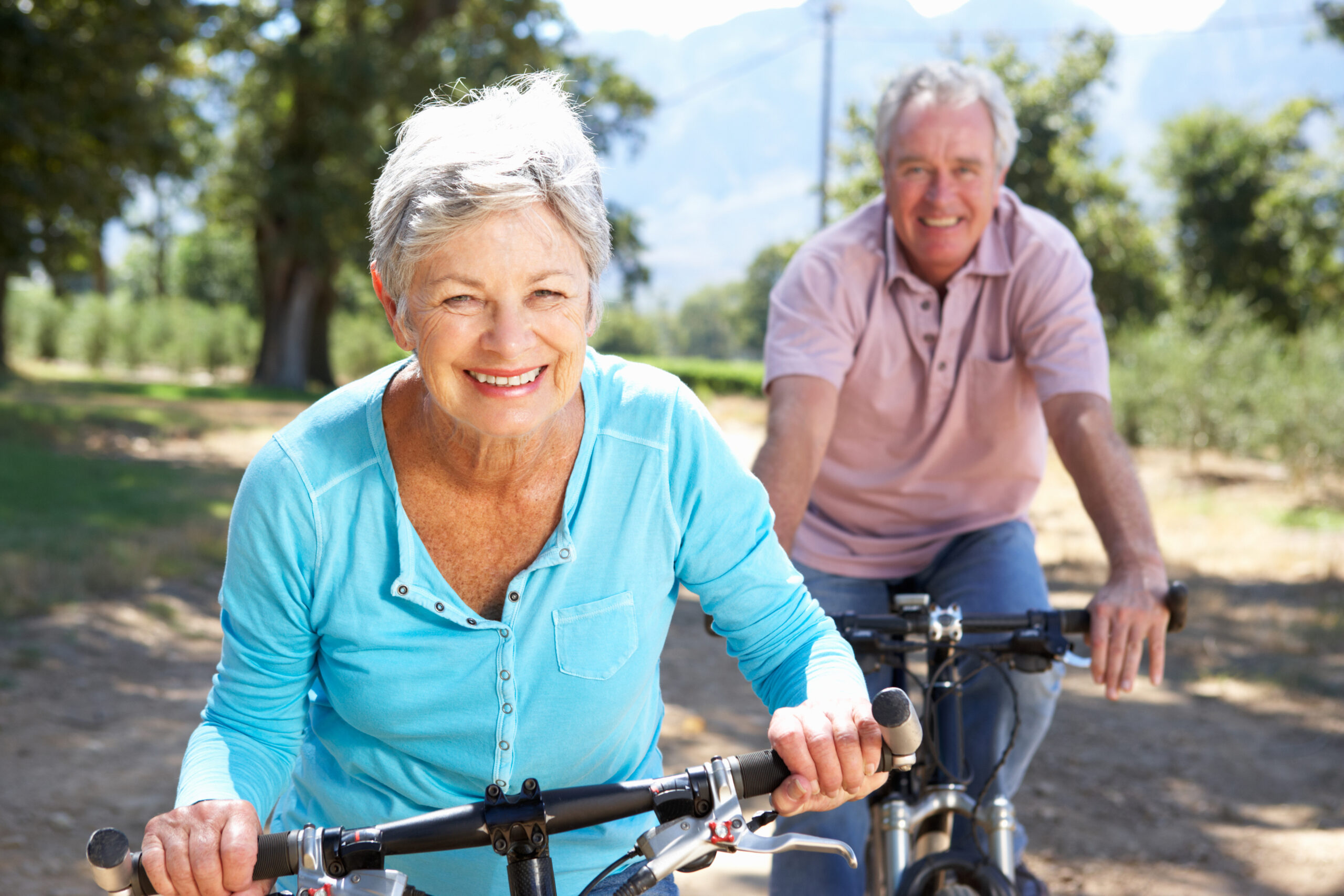 a senior couple riding bikes down a country road