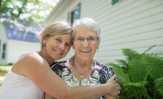 Senior and adult child hugging | Seeking out memory care and a dementia care plan