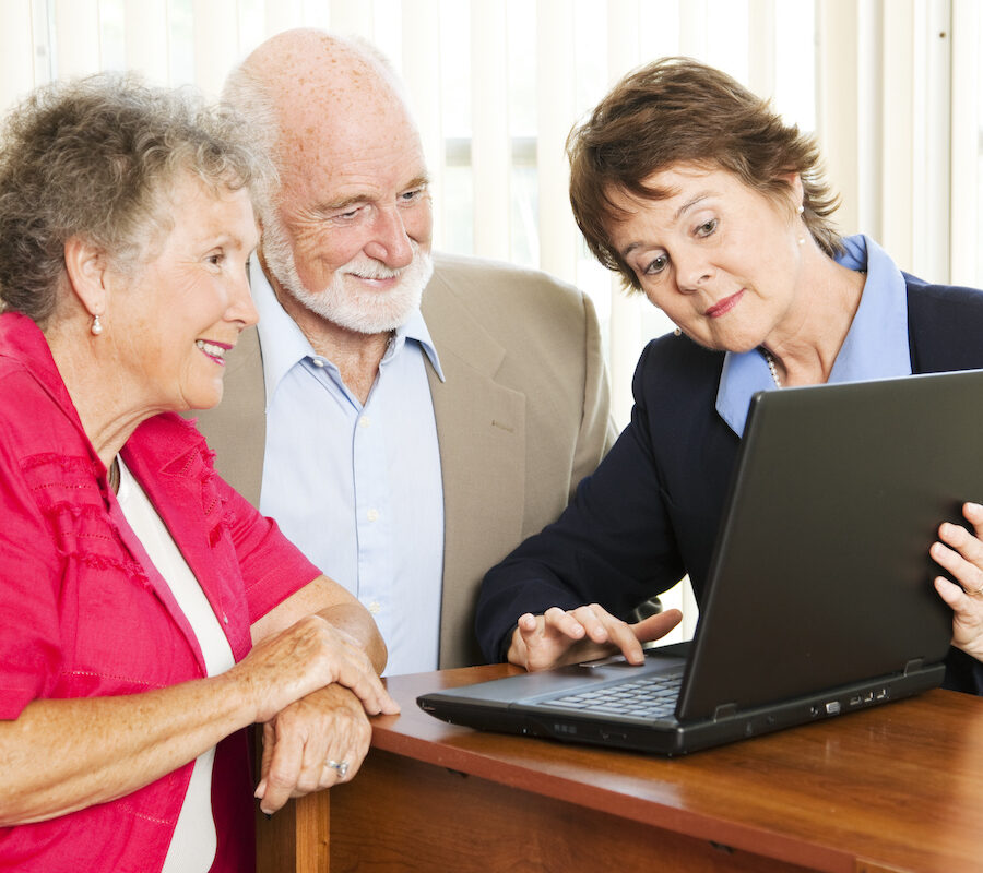 Senior man and woman talking to a younger woman while reviewing information on a laptop