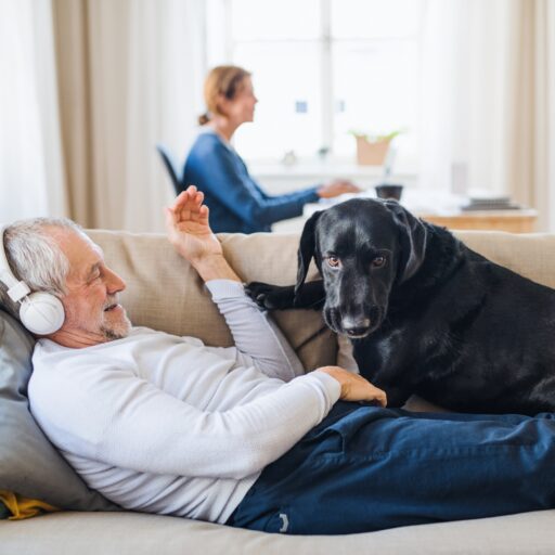 Senior listening to headphones with dog | benefits of audiobooks