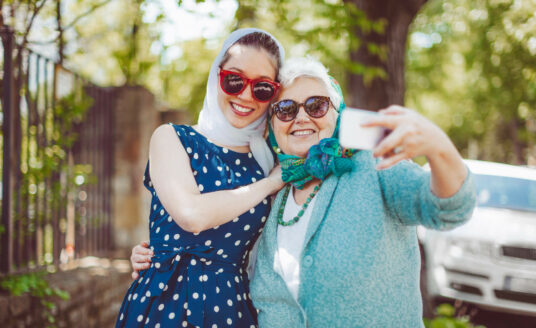 Senior woman and grand daughter smiling for the camera while taking a selfie