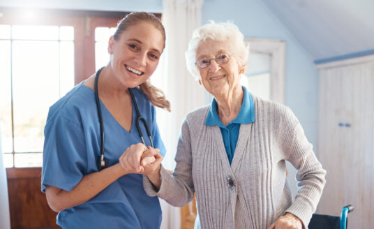 Senior care nurse helping elderly woman